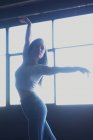 Молодая девушка в джинсах танцует, глядя на пол под солнцем — стоковое фото
