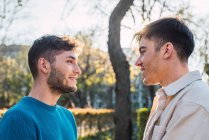 Vista lateral de casal homossexual encantado de homens olhando uns para os outros no parque — Fotografia de Stock
