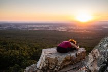 Молодая женщина йога практикует йогу на скале в горах со светом восхода солнца — стоковое фото