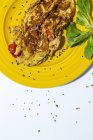Délicieuse omelette au persil haché sur assiette contre tomates séchées au soleil sur fond blanc — Photo de stock