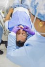 Estomatologista feminina em máscara uniforme e respiratória curando dentes de paciente do sexo masculino no hospital — Fotografia de Stock
