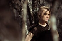 Ritratto di giovane bella donna bionda in una foresta, illuminazione drammatica sul suo viso — Foto stock