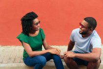 Black couple sitting on the street and looking to the side — Stock Photo