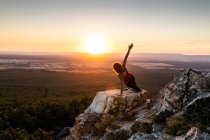 Junge Yogi-Frau praktiziert Yoga auf einem Felsen im Gebirge im Licht des Sonnenaufgangs — Stockfoto