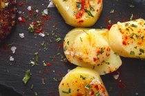 Vista dall'alto del tentacolo di polpo fritto e pezzi di patata serviti con spezie su tavola nera — Foto stock