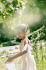Conteúdo adolescente em vestido de balé brincando com pano transparente no prado no parque no dia ensolarado — Fotografia de Stock