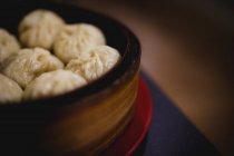 Caliente delicioso al vapor xiaolongbao en cesta de bambú en la mesa en la cocina del restaurante asiático - foto de stock