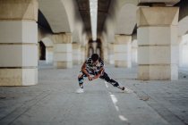 Junge, fitte Afroamerikanerin streckt Beine, bevor sie auf der Straße läuft — Stockfoto
