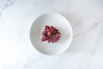 Сверху кучка сладкого розового винограда подается на тарелке на белом фоне — стоковое фото