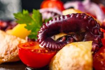Вкусный салат с осьминогом и разнообразными овощами и травами на столе — стоковое фото