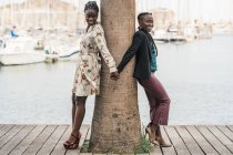 Дивна мода, що посміхається афроамериканкам проводити час разом і складати руки в парку в яскравий день. — стокове фото