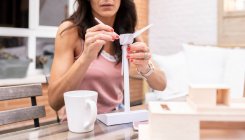 Щаслива жінка-архітектор збирає пластикову модель вітряка, сидячи за столом з ноутбуком і працюючи над проектом на терасі — стокове фото