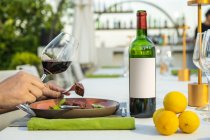 Bottiglia di vino e costumista che tiene un bicchiere al ristorante di alta cucina all'aperto — Foto stock