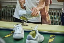 Trabajador haciendo su tarea en la línea de producción de zapatos en la fábrica de zapatos chinos - foto de stock