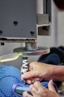 Деталь рабочих, делающих дырки для шнурков на китайской обувной фабрике — стоковое фото