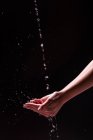 Вид на рослину анонімної жінки, що миє руки з бризкою води на чорному тлі — стокове фото