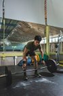 Focalisé asiatique athlète masculin faisant haltérophilie avec haltère lourde pendant l'entraînement dans la salle de gym regardant vers le bas — Photo de stock