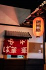 Red cloth with Asian hieroglyphs in window with metal roof of modern building — Stock Photo