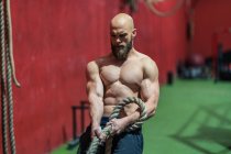From above strong sportsman pulling rope with heavy weights during intense workout in contemporary gym — Stock Photo