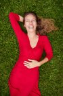 Жінка в червоному одязі лежить на землі в парку з травою — стокове фото