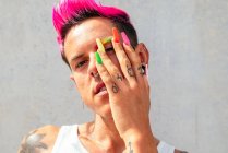 Confiante gay masculino com longo colorido unhas olhando para câmera no rua no ensolarado dia — Fotografia de Stock