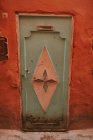Кровавая стена старого дома со старой дверью на улице Марракеш, Марокко — стоковое фото