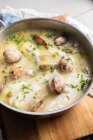 Von oben Ansicht des Metalltopfs mit köstlichen Meeresfrüchten Suppe mit Venusmuscheln und Seehecht auf Holzbrett in der Küche platziert — Stockfoto