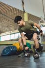 Asiatique homme formation épaules et les bras avec de lourdes kettlebells dans la salle de gym pendant l'entraînement fonctionnel et regarder loin — Photo de stock