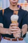 Colheita mão tatuada de macho com sorvete doce em cone de waffle na rua — Fotografia de Stock