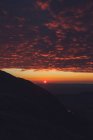 Захватывающие пейзажи яркого оранжевого солнца в вечернем небе над горным хребтом Уэльса — стоковое фото