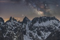 Чудовий краєвид грубих скелястих гірських вершин вкритий снігом під зоряним небом з Чумацьким Шляхом. — стокове фото