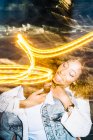 Fröhliche junge Afroamerikaner geben Huckepack-Fahrt zu glücklichen Freundin mit lockigem Haar in trendigen Outfit in der Nähe von Freeze Lights — Stockfoto