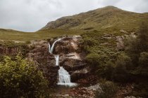 Вид на невеликий водоспад у скелях і папороті в гірській долині Гленко (Об 