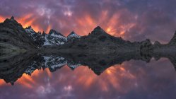 Paisagem espetacular de montanhas cobertas de neve ao pôr do sol refletida em um lago — Fotografia de Stock