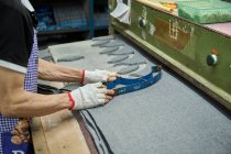 Detalhe do trabalhador usando o padrão de corte ao cortar tecido na fábrica de sapatos chineses — Fotografia de Stock