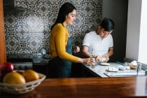 Amare madre etnica e ragazzo adolescente con sindrome di Down preparare la pasta mentre si cucina insieme in cucina a casa — Foto stock