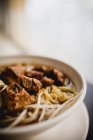 Gros bol de délicieuse soupe de nouilles asiatiques avec côtes de porc placé sur la table de café — Photo de stock