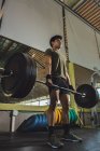 Focalisé asiatique athlète masculin faisant haltérophilie avec haltère lourde pendant l'entraînement dans la salle de gym — Photo de stock