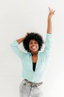 Juguetón joven afroamericano hembra en traje de moda divertirse y mostrar la lengua y la paz signo sobre fondo blanco - foto de stock
