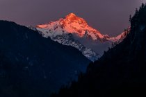 Montañas rocosas del Himalaya cubiertas de nieve iluminadas por la brillante luz del sol naranja en Nepal - foto de stock