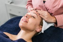 Cortada massagista irreconhecível massageando ombros de cliente feminino deitado na mesa no salão de beleza — Fotografia de Stock