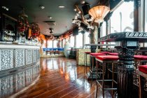 Interior acolhedor de bar espaçoso com balcão de madeira e mesas iluminadas por lustres brilhantes — Fotografia de Stock