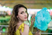 Seitenansicht der kindlichen Frau, die süße blaue Zuckerwatte isst, während sie Spaß hat und das Wochenende auf dem Festplatz im Sommer genießt — Stockfoto
