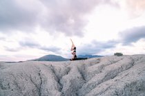 Side view of woman balancing upside down on arms of man during acroyoga session in mountains — Stock Photo