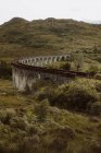 Стара залізнична колія вздовж стародавнього арочного мосту біля гори Хілл у сірий день у Гленфіннані, сільській місцевості Великої Британії. — стокове фото