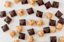 Vue du dessus de délicieux bonbons au chocolat avec des noix en forme de cœur éparpillés sur fond blanc — Photo de stock