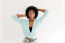 Brincalhão jovem afro-americano feminino olhando para a câmera na roupa da moda se divertindo tocando afro cabelo no fundo branco — Fotografia de Stock