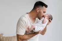 Ніжний батько стоїть з милим сплячим немовлям біля стіни в кімнаті вдома — стокове фото