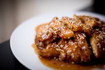 Preparato saporito pollo piccante su piatto bianco su tavolo di legno in ristorante asiatico — Foto stock