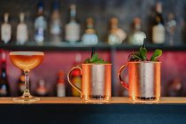 Mule de Moscou et cocktails aigre servis avec verre et glaçons sur le comptoir dans le bar — Photo de stock